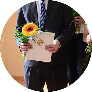 Mann mit Zeugnis und Blume in der Hand